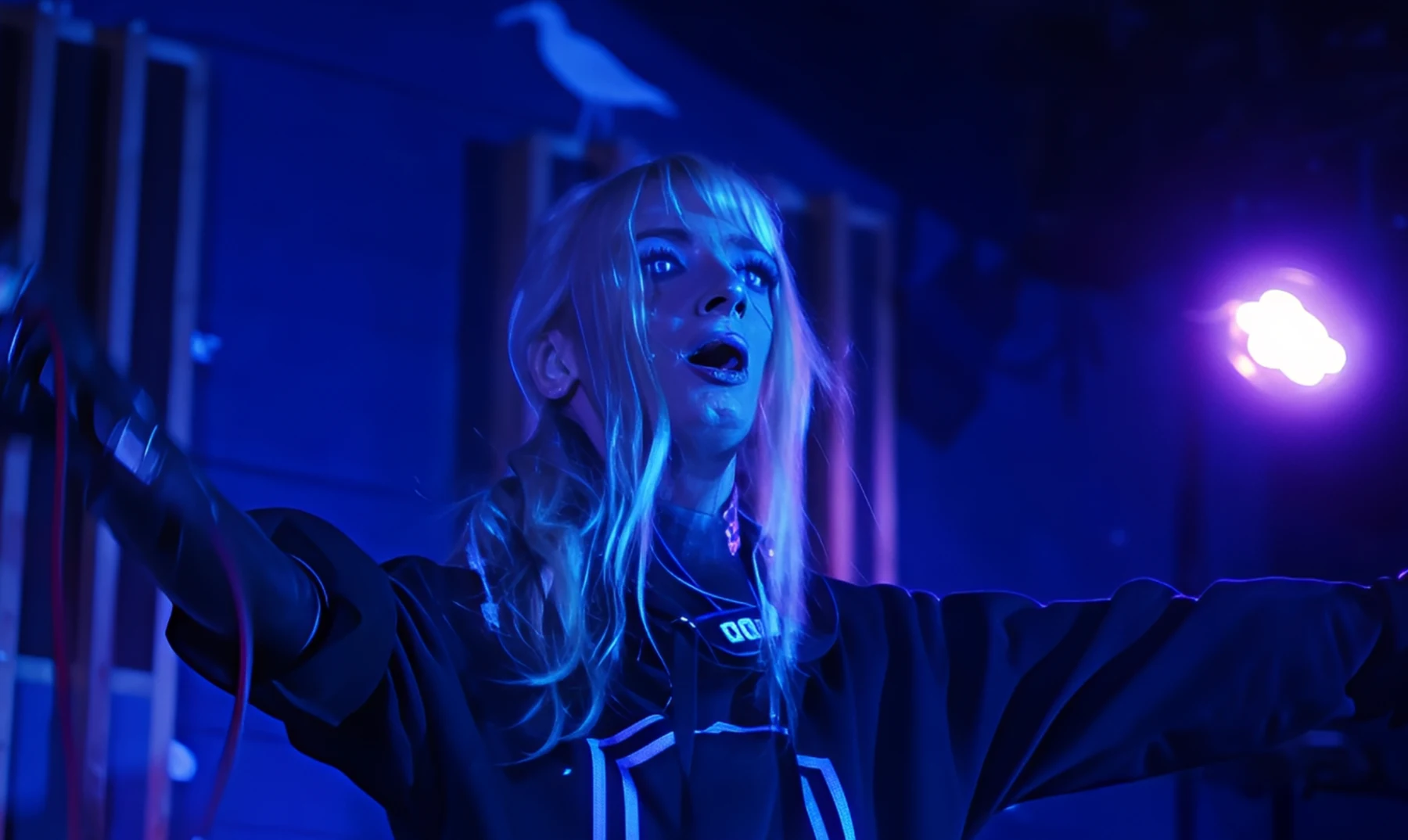 Monarkki performing under blue light with arms outstretched