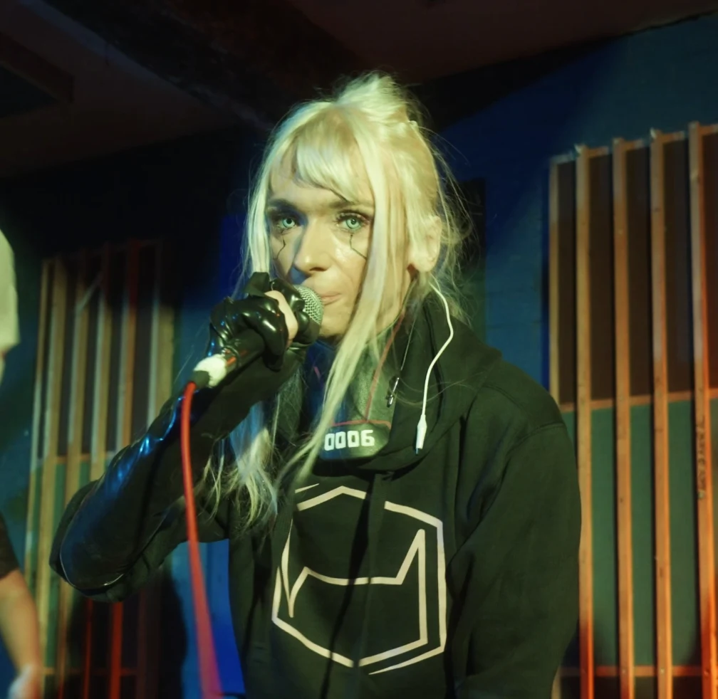 Monarkki performing into a microphone under warm stage light