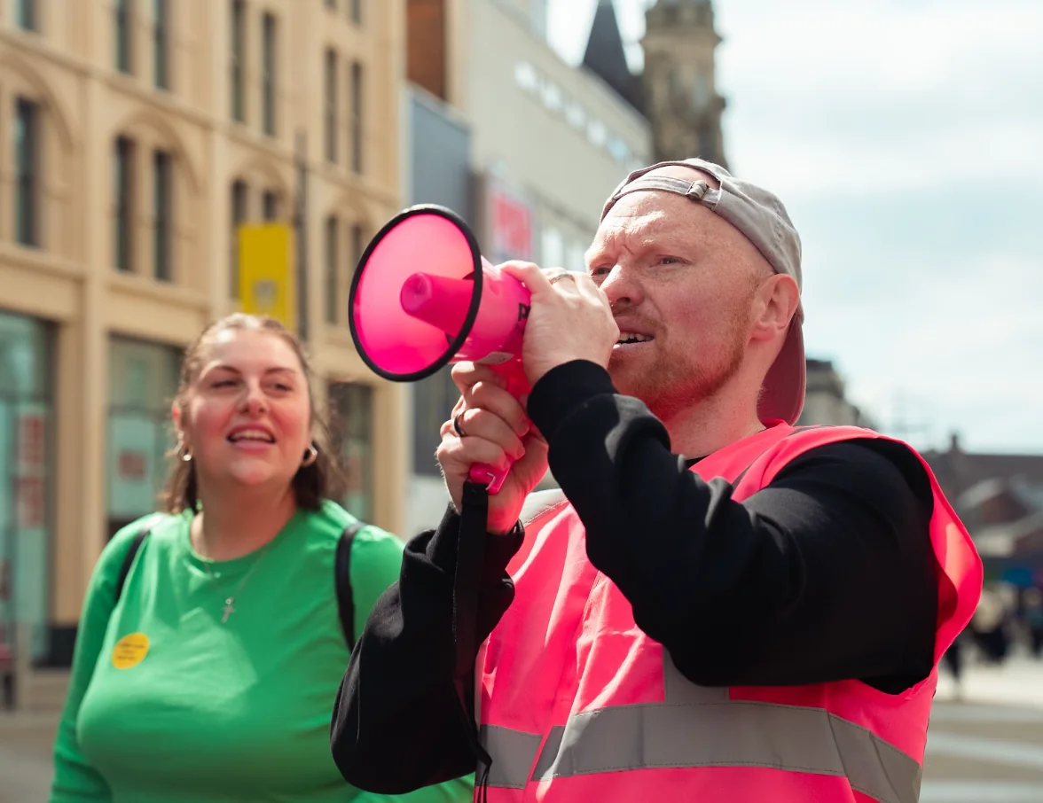 Leeds Dads protest speaker addressing the crowd with a pink megaphone