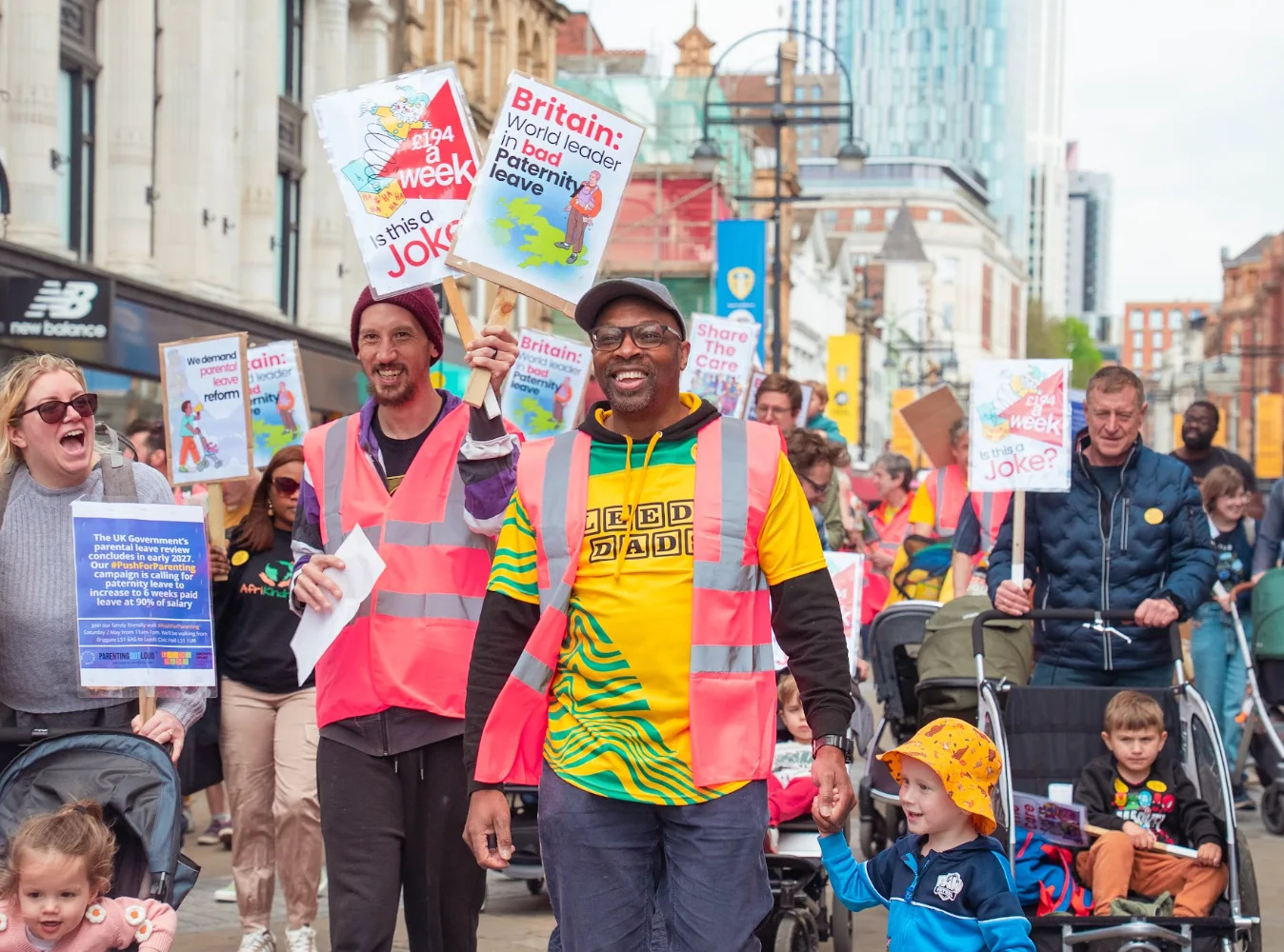 Leeds Dads marchers holding paternity leave campaign placards