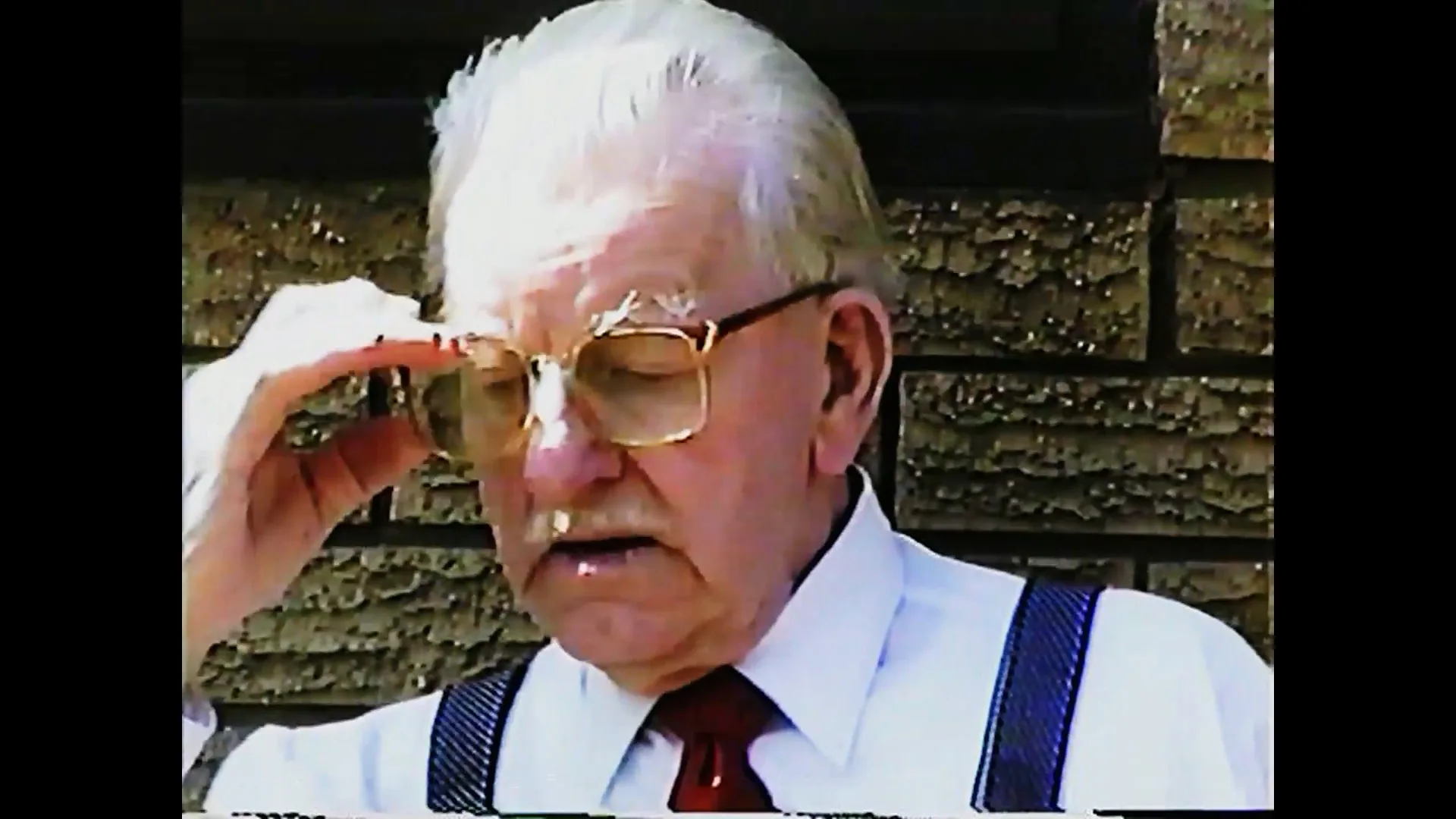 Original VHS close-up of an older man adjusting his glasses