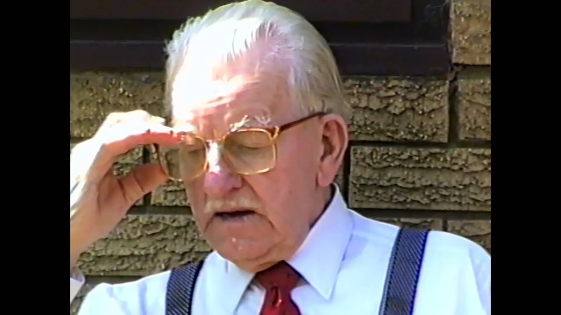 Restored VHS close-up of an older man adjusting his glasses