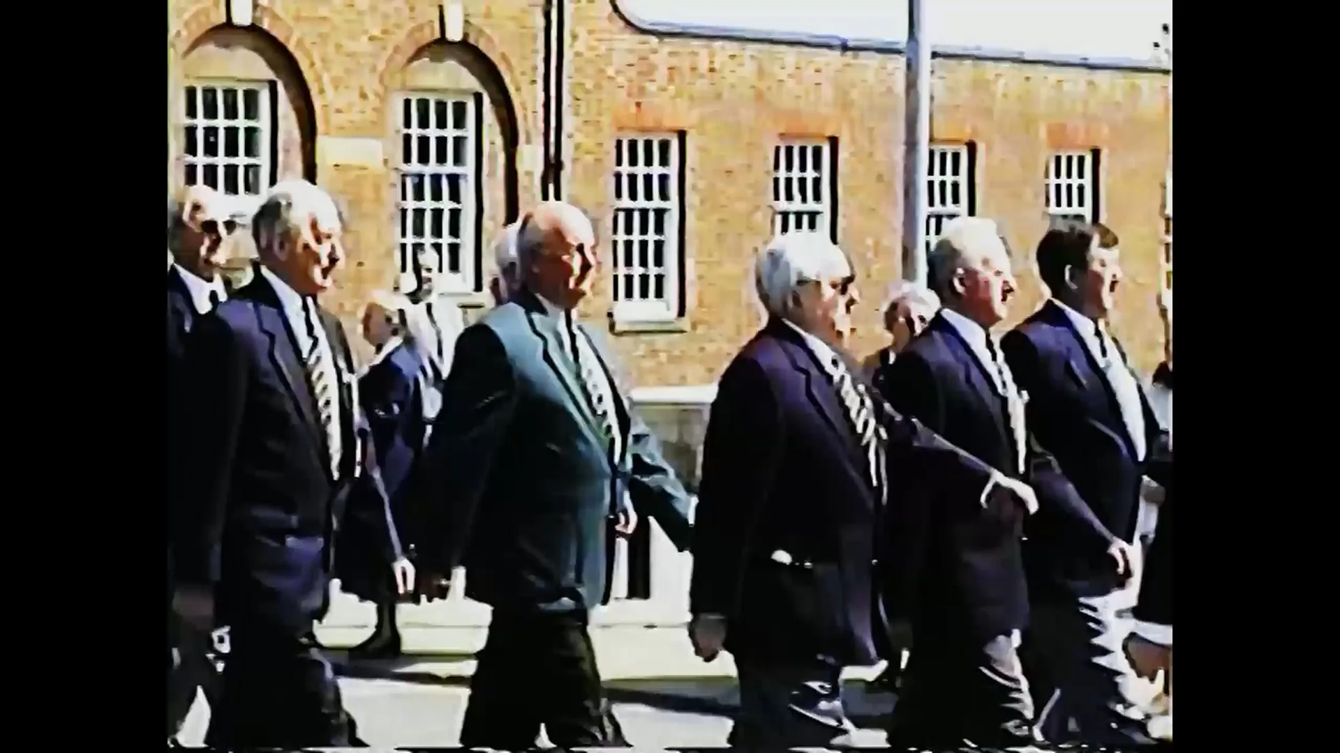 Original VHS footage of a group walking outside a brick building