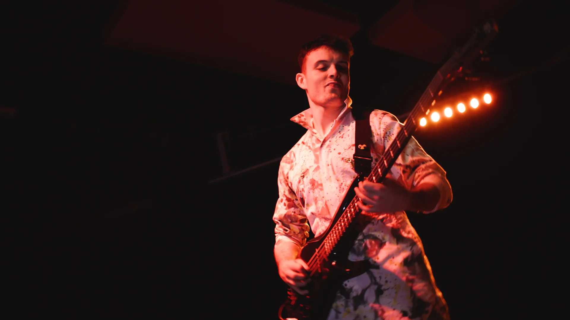 Guitar performance under red lighting in August Underground