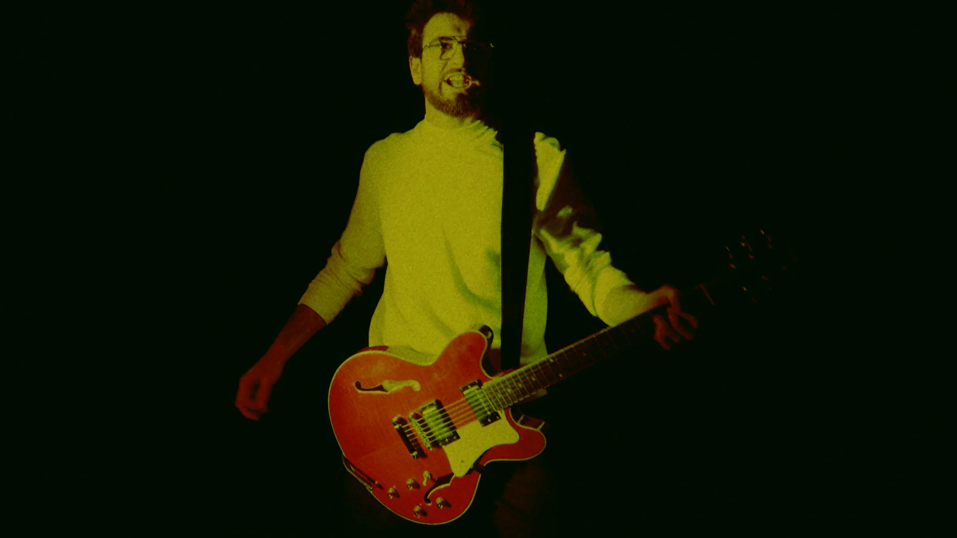 Guitarist performing under green light in I See Red